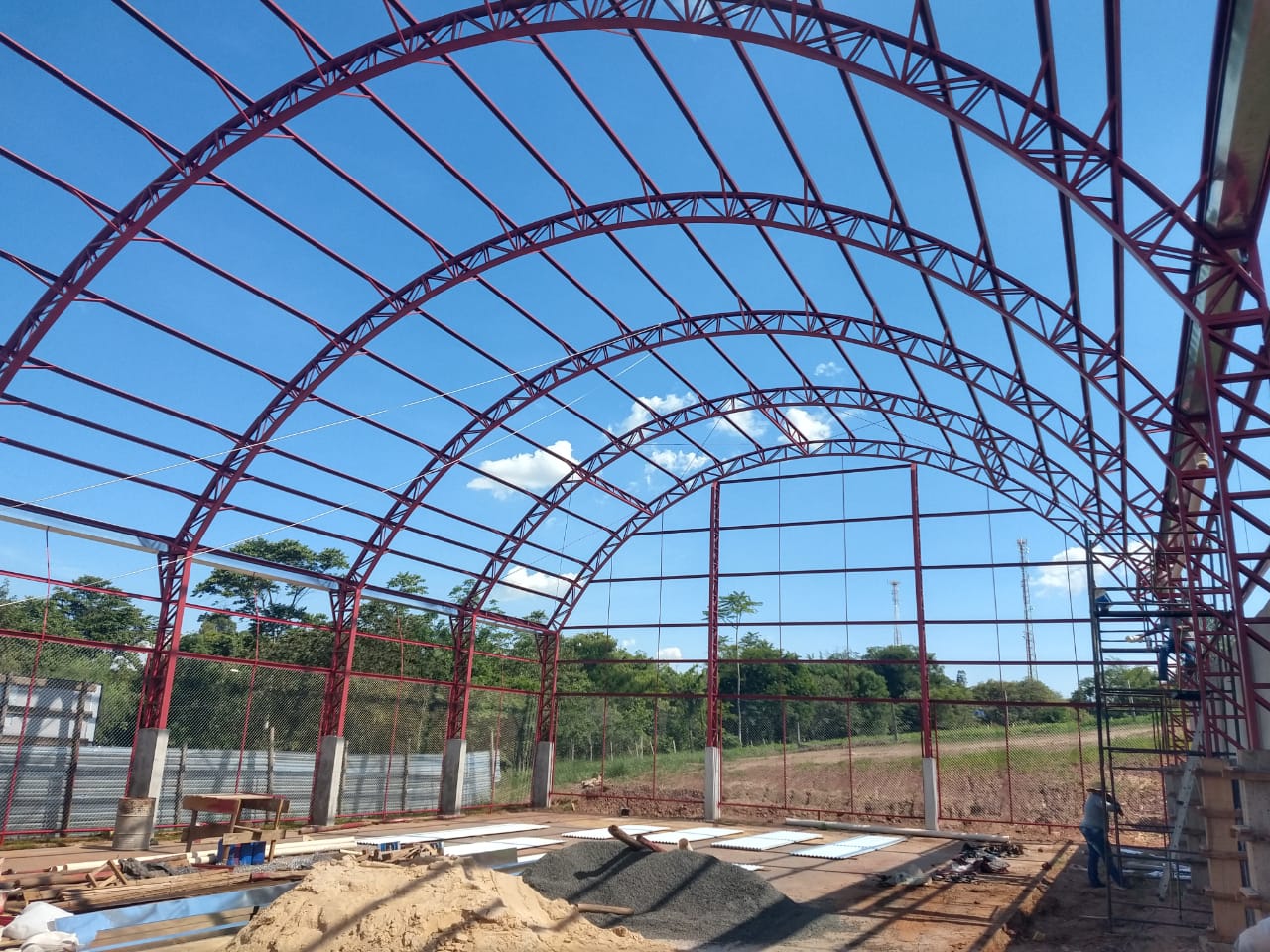 Estrutura metálica para quadra poliesportiva com 600m². Colunas metálicas treliçadas, telha galvalume ondulada.